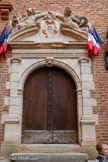 <center>Albi</center>L’Hôtel de Ville (XVIIe siècle).  la porte d'entrée de l'escalier, en plein cintre, présente un encadrement intérieur mouluré et coupé par la clef en console. Il est accosté de pilastres nus à chapiteaux ioniques. Au-dessus d'une frise bombée, un fronton circulaire rompu encadre un cartouche, délimité par des volutes. Reposant sur les rampants du fronton, sont sculptés deux personnages ailés tenant des rameaux de feuillages enlacés ainsi que des cornes d'abondance remplies de fruits.