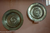 <center>Najac : Église Saint-Jean l’Évangéliste.</center>Ces plats de quête (diam. 36 cm et 39,5 cm)en laiton martelé étaient utilisés lors des offices liturgiques afin de collecter les dons.
Un motif de godrons (soleil tournoyant ou roue solaire) en orne la partie centrale. Une inscription en langue allemande figure sur l’un d’eux. Fréquents dans le Rouergue, ces plats pourraient provenir de Nuremberg ou des Flandres (Dinant-sur-Meuse). Ils pourraient également avoir été réalisés par des dinandiers allemands installés dans le Rouergue ou par des dinandiers locaux Villefanche-de Rouergue était alors un important centre de production et de commercialisation du cuivre) ayant acquis des matrices.