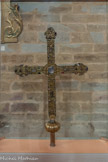 <center>Najac : Église Saint-Jean l’Évangéliste.</center>Croix reliquaire, et processionnelle. (XIIIe ou XIV siècle). Travail italien, Vénétie ?
(h. 90 cm, 156,5 cm).
Objet classé au titre des Monuments Historiques (1908)
Cette exceptionnelle croix de procession, qui fut restaurée à plusieurs reprises, dont en 2018, passe pour avoir été offerte anciennement à la paroisse par la famille de Sénezergues.
Constituée d’une âme en bois couverte de plaques d’argent doré et de filigranes d’argent dorés et cloués, d’un nœud et d’une douille en cuivre doré, la croix est ornée de nombreux gemmes, de gros cristaux de roche ainsi que de quatre reliquaires sous verre.