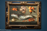<center>Le musée Goya.</center>Baltazar GOMES FIGUEIRA
ÔBIDOS (PORTUGAL), 1604 - ID., 1674
Nature morte au poisson avec crabe, crevettes, oignons et oranges
1645
Huile sur toile
Baltazar Gomes Figueira est l’un des plus grands artistes du Portugal au XVIIe siècle. Formé à Séville, où il reçoit l'enseignement de Francisco Herrera le Vieux, cet artiste baroque applique toute sa technique à la peinture des bodegones, spécificité hispanique dans le genre des natures mortes caractérisée par la présence quasi exclusive d'aliments et montrant parfois des marchands ou des cuisiniers.
Cette Nature morte au poisson avec crabe, crevettes, oignons et oranges est d’abord saisissante par la rigueur et le dépouillement de sa composition. Chaque élément est traité avec une impon tance égale créant ainsi un équilibre parfait. Suspendus, les oranges et oignons donnent une grande légèreté à la composition. Attentif à l’illusion réaliste des choses, le peintre soigne le relief et les textures de chaque élément. Les écailles du poisson, la peau rugueuse des oranges, la carapace brillante du crabe sont autant de détails figurés. Le poisson est lui aussi peint de manière très réaliste, les empâtements transcrivant avec précisions Jusqu'aux détails des branchies.