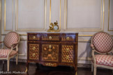 Musée des Arts Décoratifs. Salon de compagnie<br> La commode est un meuble d’ébénisterie parisienne, vers 1775, caractéristique du style Transition Louis XV-Louis XVI : façade et montants rectilignes associés à un tablier légèrement chantourné et des pieds en console. La très riche et élégante marqueterie d’essences variées en réseau de cubes, frise d’entrelacs, bouquet, a été restaurée par l’AFPA de Chartres en 2002. Sur le marbre, la pendule, en bronze doré, est une allégorie des Arts ; cadran signé Lemoyne à Paris, XVIIIème siècle.