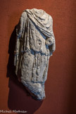 Musée d'Aquitaine. <br> Statue de Cautopatès.
 Fin du IIee siècle - lère moitié du IIIe siècle Calcaire.
Cautopatès est, avec Cautès, l’un des deux compagnons de Mithra, dieu dont le culte, d’origine orientale, connut un essor considérable dans tout l’Empire romain à partir de la fin du IIe siècle et s’éteignit, concurrencé par le Christianisme, au cours du IVe siècle. Bien que tendant vers le monothéisme, ce culte à mystères pénétré d’astrologie comprend des rites d’initiation et une célébration - sacrifice du taureau et repas rituel - tout à fait particuliers. Il est honoré dans des grottes ou des sanctuaires enterrés, et seuls les hommes y sont apparemment admis.
Il célèbre la lumière et la force, et prône des valeurs telles que fraternité, égalité et loyauté qui le firent particulièrement apprécier des soldats, mais aussi des commerçants et des voyageurs pénétrés de ces rites adoptés en Orient, des artisans, des affranchis, et des esclaves qui y retrouvaient en quelque sorte une famille.
La statue de calcaire présente Cautopatès selon l’usage : il est habillé à l’orientale comme le dieu Mithra lui-même, avec le bonnet phrygien et la cape colorés de rouge. Contrairement à son compère Cautès qui, debout, jambes croisées, tient sa torche levée et symbolise la lumière, le jour, le renouveau..., Cautopatès, torche baissée, représente en symétrie le crépuscule, l’automne, ...la mort.