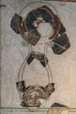 La Villa gallo-romaine et le Musée de Plassac. <br> Masque lunaire portant un médaillon à fleuron rouge vermillon. De la tête très ronde, sur fond noir, sortent deux cornes en forme de lyre qui soutiennent un médaillon à fleuron. Cette tête faisait partie de la zone supérieure du décor.