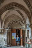 <center>Beaune </center>Le portail du bras droit du transept ouvre sur une galerie de cloître à sept travées. Il est cantonné de deux voussures à rinceaux et de quatre colonnes dont les chapiteaux sont sculptés de décors végétaux, de deux femmes-oiseaux et d’un combat de coqs.