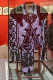 <center>Musée Taurin à Béziers. </center>Costume goyesque offert à la Ville de Béziers par le matador biterrois Sébastien Castella le 15 juin 2015. La soie qui fait partie de sa composition le rend brillant, attirant, tissu noble cousu sur du jersey permettant les multiples mouvements du torero, c'est son costume qui se dévoile sous nos yeux. Sa veste (chaquetilla), moderne, respirant les heures de travail qui lui avait été dédié ., avait un côté glorieux et courageux. Le pantalon (taleguilla) avait de somptueuses broderies. Elles attiraient l'œil, et formaient des cœurs plus délicats les uns que les autres.