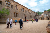 <center>Abbaye de Fontfroide.</center>La cour d’honneur est aménagée entre le XVIe et le XVIIIe siècle. Ce mur immense cache, au rez-de-chaussée, le réfectoire des convers, puis, après la porte romane, le cellier, et à l'étage leur dortoir. Ces bâtiments sont situés à l'Ouest, c'est-à-dire du côté où le soleil se couche. Dans la symbolique chrétienne, l'Ouest est le côté des affaires terrestres, l'Est, celui de la lumière du Christ. Fontfroide se développe très vite. Dès la première moitié du XIIIe siècle, l'abbaye a essaimé : elle a 2 