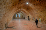 <center>Abbaye de Fontfroide.</center>L'abbatiale. Dortoir des Convers. C’est une salle à voûte de grès rose, en berceau brisé, sans aucun doubleau sur toute sa longueur. Le dortoir est à l'origine trois fois plus long. Les frères dorment sur des petits lits de bois avec une paillasse, deux couvertures, tout habillés et séparés par des petites cloisons de bois.
Le fond de cette vaste sert pour sa partie méridionale de grenier. Les convers montent les sacs de grains trop fragiles pour l’humidité du cellier. Cette salle est ce qui subsiste du dortoir des convers après des transformations au XVIIIe siècle. Imaginons la presque totalité des frères convers de Fontfroide ralliant l'abbaye pour un dimanche de Pâques... Entre 200 et 250 frères, qui, 1e soir, viennent se reposer ici, dans ce dortoir. Il est alors 3 fois plus grand, couvrant la surface de l'escalier actuel et au-delà. De simples cloisons de bois séparent les planches couvertes d’une paillasse où ils se couchent tout habillés, roulés dans un gros drap de laine, la nuque sur l'oreiller bourré de paille.