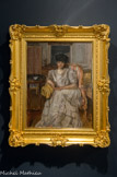 Portrait de la Princesse Hélène de Caraman-Chimay. PIERRE BONNARD, (1867-1947). Huile sur toile, 1929
En collaborant avec Thadée Natanson, directeur de La Revue Blanche, Pierre Bonnard devient également l'ami de sa célèbre épouse d'origine polonaise, Misia Godebski, muse du groupe des Nabis et intime de la famille de Caraman-Chimay. Née Hélène de Brancovan (1878-1929), Hélène de Caraman-Chimay épouse le 24 août 1898 Alexandre de Riquet, Prince de Caraman-Chimay. Elle est la sœur de l'égérie de Proust, Anna de Noailles.
Même s'il préfère travailler dans son atelier, Bonnard se rend chez la princesse avenue Henri Martin à Paris. Le modèle est dans son intérieur, entouré de ses objets familiers. Les couleurs pastel s'accordent et se répondent pour transmettre une impression visuelle générale de bien-être et de sérénité. Le paravent, la bergère et le sofa aux lignes verticales roses, bleues et jaunes, contribuent, comme les boiseries bleues, à l'équilibre de la scène. Seule la bergère Louis XVI et le guéridon marqueté apportent quelques courbes à la scène. La robe en soie dans des camaïeux de gris bleutés est rehaussée par un jabot de dentelles et un collier de perles blanches qui éclairent le visage mélancolique de la princesse. Sa main gauche nonchalamment posée sur son genou se trouve au centre de la composition.