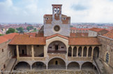 <center>Palais des Rois de Majorque.</center>Le clocher de la chapelle Sainte Croix se trouve immédiatement au-dessus de la rose, au sommet de la façade ouest de la Torre Major, le donjon du palais. Construit avec la même pierre, il était couronné eu XIVe siècle d'une flèche en bois recouverte d'étain imitant celle de le Sainte Chapelle à Paris. On ignore de quand date son aspect actuel. Toutefois, il apparaît sous cette forme sur une gravure de la fin du XVIIe siècle.