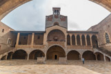 <center>Palais des Rois de Majorque.</center>Le plan du palais, très fonctionnel et novateur pour l'époque, forme pratiquement un carré de 60 mètres de côté. Il s'organise en deux grands espaces parfaitement différenciés : l'espace public autour de la plus grande cour et l'espace privé autour de deux cours plus petites. L'ensemble est dominé par la chapelle, en position centrale, qui marque la prépondérance du spirituel sur le temprel. De chaque côté, deux grands escaliers relient cette cour à l'étage à chaque extrémité d'un vaste préau surmonté d'une galerie qui longe la façade sur toute la longueur.
