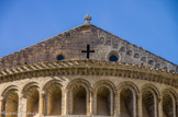 <center>Saint Guilhem le Désert. </center> Derrière l'abside, on aperçoit le mur pignon qui effectue la transition entre la nef et le chœur. Au centre s'ouvrent les deux oculi et la baie cruciforme, tandis que les extrémités des retombées du toit sont ornées de petits arcs.