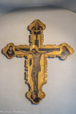 Église Santa Maria di Castello. Antoine Bréa, crucufix. Les Christe médiévaux sont représentés morts sur la croix. Les bourgeons au bout des bras représentent la vie éternelle. A gauche, un chérubin qui recueille le sang du Christ.