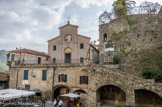 <center>Apricale.</center> L'église Purificazione di Maria Vergine date du XXe siècle. La place servait autrefois aux consuls médiévaux pour rendre justice, depuis les longs bancs de pierres situés sous les arcades.