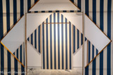Daniel BUREN
1938, Boulogne-Billancourt (France)
Cabane éclatée n° 2
1982
Bois, toile de coton à rayures verticales bleues et blanches, éléments projetés, serre-joints, acrylique blanche
inv.c.92.6 Achat 1992.À propos de la Cabane éclatée n°2, il explique : « Soit la construction d'une boîte de 420 cm de long par 280 cm de large en panneaux de 140 cm de large chacun par 280 cm de haut Chacun de ces châssis est tendu de tissu, ici blanc et bleu. Des dessins particuliers sont effectués dans ces châssis, permettant d'en ôter des fragments qui constitueront des 