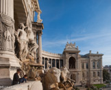 <center>Le palais Longchamp. </center> Son pied s'appuie sur une corne d'abondance. De son char, l’eau tombe en cascade dans un bassin.