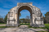 <center>L'arc de triomphe de Glanum.</center>Construit vers la fin du règne d'Auguste au côté du mausolée des Julii, qui lui est antérieur de quelques décennies, il constituait avec lui le symbole visible de la puissance et de l'autorité romaines. Ses proportions parfaites (12,5 m de longueur, 5,5 m de largeur et 8,6 m de hauteur) et la qualité exceptionnelle de son décor sculpté dénotent une influence grecque. La partie supérieure de l'arc, qui devait comprendre une inscription dédicatoire, est manquante. 
Les sculptures décorant l'arc illustrent à la fois la civilisation de Rome et le destin funeste de ses ennemis. Des groupes de captifs enchaînés et des étendards ornent les façades du monument. Les fruits et les fleurs qui décorent l'archivolte des deux arcs de tête de la voûte à caissons de l'Arc signalent les bienfaits et l'abondance que Rome a apportés à la Gaule. De même, les quatre victoires ailées, porteuses de branches de laurier et d'étendards, sculptées dans les écoinçons, célèbrent la gloire de Rome.