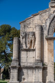 <center>L'arc de triomphe de Glanum.</center>Face nord, gauche. A gauche et à droite de la baie, deux couples symétriques de Gaulois et Gauloises sont enchaînés à un poteau qui constitue un trophée. Les attitudes sont douloureuses mais dignes.