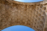 <center>L'arc de triomphe de Glanum.</center>La voûte est ornée de cent dix caissons hexagonaux en forme de nids d'abeille remarquablement ciselés. Elle est soulignée par des bandeaux de fruits (grenades, pommes, raisins), de rameaux d'olivier et de rinceaux de fleurs. Elle évoque par son exubérance les bienfaits de la paix et de la civilisation, en contraste avec la thématique guerrière des bas-reliefs sur les côtés.