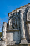 <center>L'arc de triomphe de Glanum.</center>Face sud, gauche. Un prisonnier, vêtu d'un manteau gaulois, avec un homme plus petit, portant son manteau à la romaine et posant sa main sur l'épaule du prisonnier.