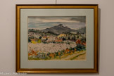 <center>Centre d’art Sébastien</center>Yves Brayer, (1907-1990)
Amandiers en fleurs aux Baux,
1980
Aquarelle. 48 x 63 cm. Collection Musée Brayer. Les Baux de Provence. <br> 25
Yves Brayer (1907–1990)
Peintre figuratif français, connu pour ses paysages lumineux de
Provence, de Camargue et ses scènes de voyage. Fidèle à la réalité,
il privilégie une peinture claire, structurée et colorée, sans jamais
céder à l’abstraction. Maître du dessin et de la lumière, il excelle
aussi bien à l’huile qu’à l’aquarelle ou à la gravure. Son œuvre,
humaniste et poétique, célèbre la beauté du monde avec force et
sensibilité.
Enraciné dans la tradition de l’École de Paris, son œuvre se
distingue par une fidélité constante à la réalité, qu’il traduit à
travers une approche personnelle, riche en couleur, lumière et
émotion. Refusant les avant-gardes abstraites, il choisit d’explorer
le monde par l’observation directe et le regard attentif, nourri de
voyages et de paysages : l’Espagne, l’Italie, le Maroc, l’Égypte, le
Japon, le Mexique ont nourri son œuvre d’influences diverses, qu’il
a su intégrer sans jamais perdre son identité plastique.
Chaque pays rencontré est restitué à travers sa lumière propre et
ses couleurs dominantes : noirs profonds pour l’Espagne, rouges
chauds pour l’Italie, verts et ors pour la Provence.