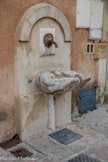 <center>Une curieuse fontaine </center>L’eau sort d’une minuscule tête de lion pour tomber dans une vasque faite d’énormes mains. Fontaine de 1992.