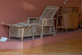 <center>Musée de la vannerie</center>CHAISE LONGUE Vietnam, région du Tonkin ?
Fin du XIXe siècle / début du XXe siècle
Bambou, rotin, pointes métalliques. Cet objet est constitué de deux matières principales : du bambou pour les parties droites (pieds, dossier) et du rotin pour tous les autres éléments, en particulier les ornementations. Quelques pointes en métal assurent sa cohésion. L'usage et le temps ayant fragilisé sa structure, une restauration s'est imposée afin de la nettoyer, la consolider et assurer sa pérennité.