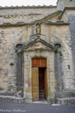 <center>L'église paroissiale Notre-Dame à Venasque. </center>A l'inverse du portail roman en retrait de la façade principale, la porte d'accès côté sud semble, elle, venir à l'avant des fidèles. La maçonnerie forme, en effet, un arrondi en saillie par rapport au mur. C'est notamment ce mouvement ondulatoire qui rapproche cette porte du style baroque. Le fronton triangulaire surplombant l'entrée est orné d'une inscription entourée d'un motif de guirlande. Au sommet de la porte, une statuette de la Vierge est placée dans une niche. Sa gestuelle des bras croisés sur la poitrine exprime sa dévotion à la mission qui lui a été confiée. Placée au-dessus de la porte, la statue rappelle le vocable de l'église dédiée à Sainte-Marie.